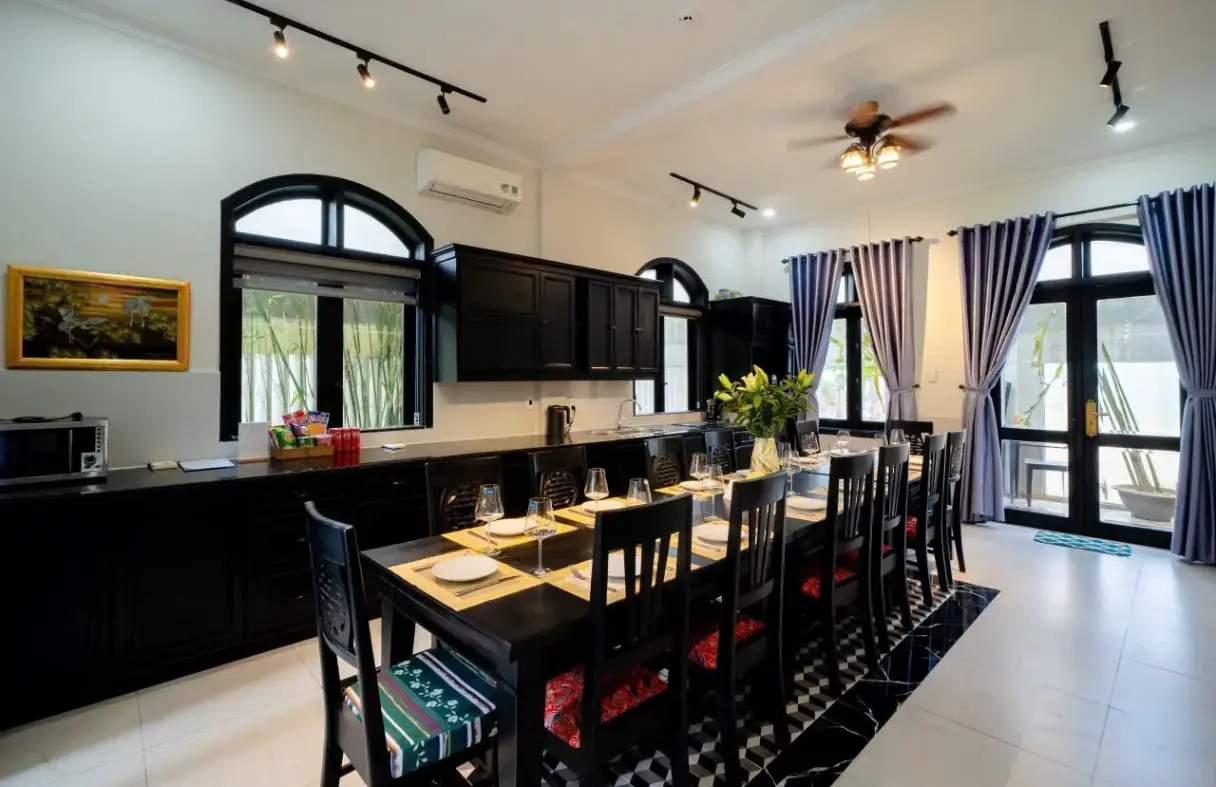 Không gian bếp và bàn ăn của villa cổ điển Đà Nẵng, nội thất gỗ tối màu và trần cao thoáng đãng