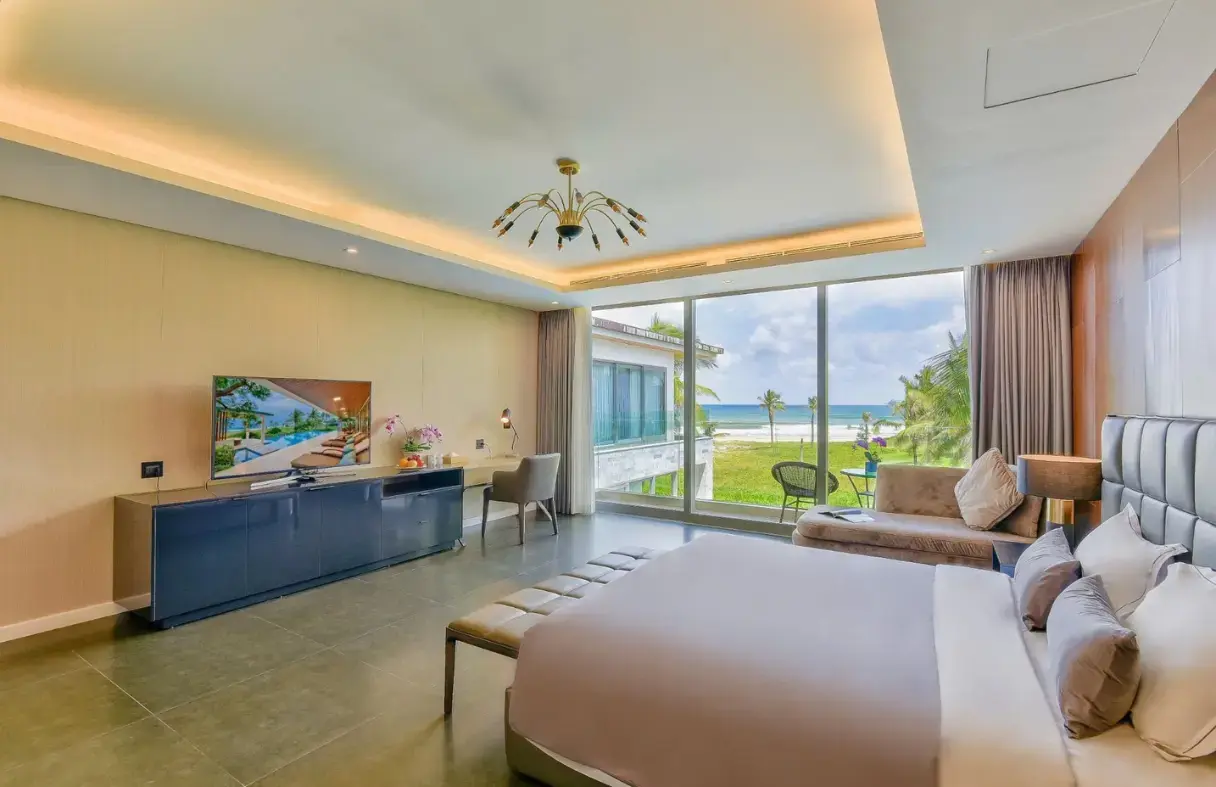 Phòng ngủ chính suite trong villa Đà Nẵng cao cấp với giường cỡ king, nội thất gỗ sang trọng và view biển ban công